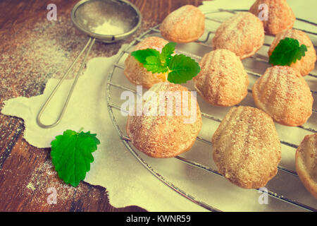 Les cookies fraîchement sortis de la crépine, madeleines au sucre en poudre. Banque D'Images