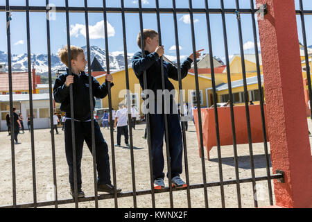 Les jeunes garçons jouant sur l'aire de récréation ; clôture ; Ushuaia Argentine Banque D'Images