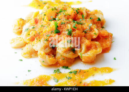 Prêt plat de pâtes surmonté de potiron, tomate, l'huile et le persil. Plaque blanche sur fond blanc. La cuisine italienne. Banque D'Images