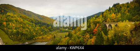 Panorama avec décor de l'automne avec le lac Izvorul Muntelui et forêt colorée et maisons en Neamt, Roumanie Banque D'Images