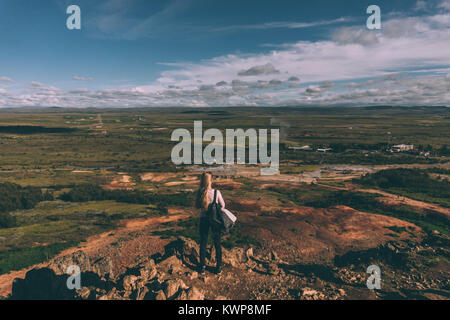 Back view of young woman standing on cliff et regardant le paysage majestueux en Islande Banque D'Images