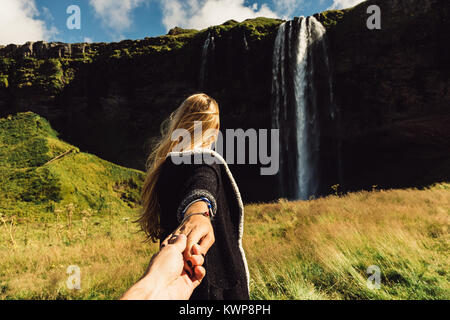 Cropped shot of girl holding hand d'ami et d'aller à la majestueuse cascade en Islande Banque D'Images