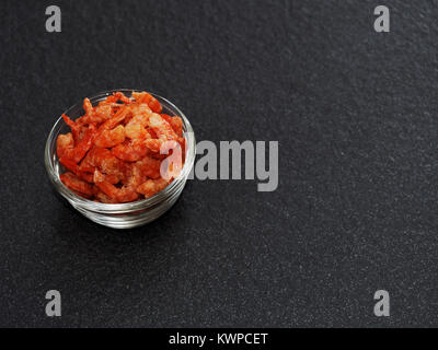 Crevettes crevettes séchées ou dans un bol en verre isolé sur fond sombre utilisé comme ingrédient en thaï salade de papaye verte Banque D'Images