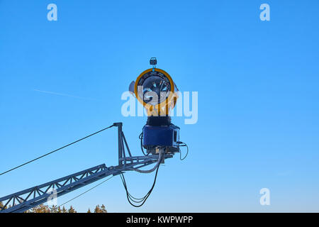Éteint neige jaune cannon suspendu dans l'air sur une piste de ski de Winterberg Carrousel contre un ciel bleu clair Banque D'Images