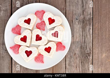 Valentines Day cookies en forme de coeur avec de la confiture et les bonbons sur une plaque blanche sur un fond de bois rustique Banque D'Images