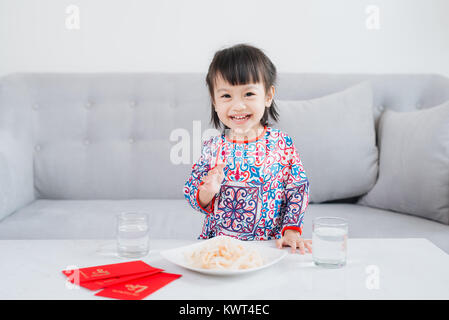 Petite fille vietnamienne en ao Dai, robe traditionnelle fêter le nouvel an à la maison. Du Têt. Banque D'Images