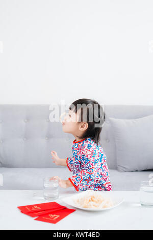 Petite fille vietnamienne en ao Dai, robe traditionnelle fêter le nouvel an à la maison. Du Têt. Banque D'Images