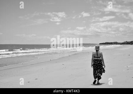 Les femmes de marcher seul sur une plage tropicale à distance, Balgal Beach, Queensland, Australie Banque D'Images