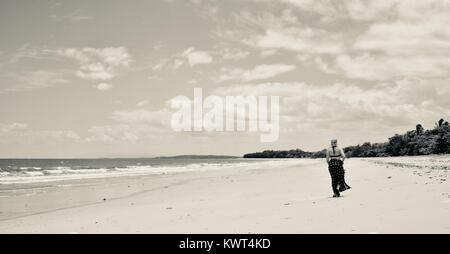 Les femmes de marcher seul sur une plage tropicale à distance, Balgal Beach, Queensland, Australie Banque D'Images