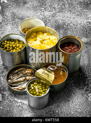 Divers aliments en conserve de viande, poisson, légumes et fruits en boîtes de conserve. Sur un fond rustique. Banque D'Images