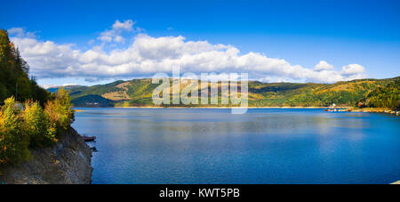 Panorama avec décor de l'automne avec le lac Izvorul Muntelui et forêt colorée et maisons en Neamt, Roumanie Banque D'Images