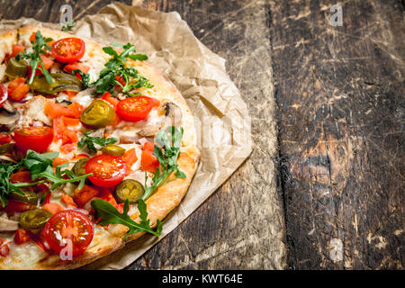 Pizza aux tomates fraîches et des verts. On a wooden background Banque D'Images