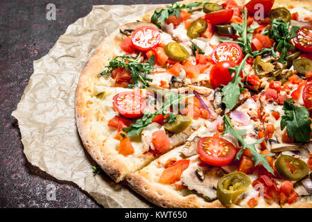 Pizza aux tomates fraîches et des verts. On a wooden background Banque D'Images