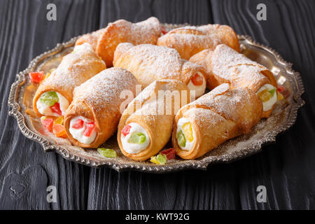 Cannoli siciliens de ricotta, fruits confits et de sucre en poudre sur une assiette sur une table horizontale. Banque D'Images