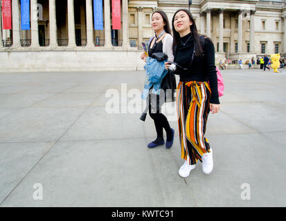 Londres, Angleterre, Royaume-Uni. Deux touristes asiatiques passant la National Gallery, Trafalgar Square Banque D'Images