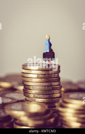 Libre d'une femme portant une valise miniature, sur le sommet d'un tas de pièces en euros, avec un peu d'espace vide en haut Banque D'Images