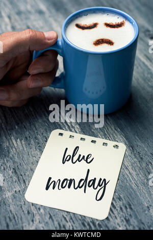 Libre d'une note avec le texte écrit en bleu lundi sur une table rustique gris et d'un jeune homme de race blanche avec une tasse de Cappuccino avec un triste fa Banque D'Images