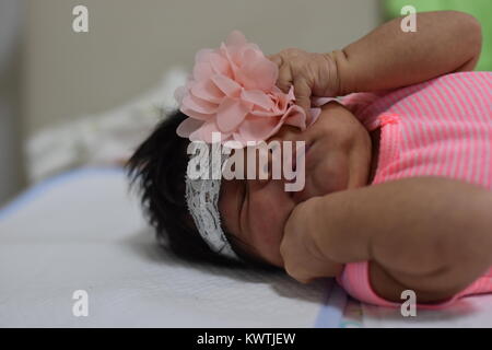 Naissance bebe Fille teint foncé vêtements rose en fixant les yeux fermés Banque D'Images