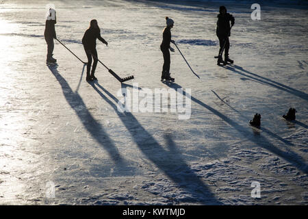 Les joueurs de hockey sur glace sur un étang en fin d'après-midi Banque D'Images