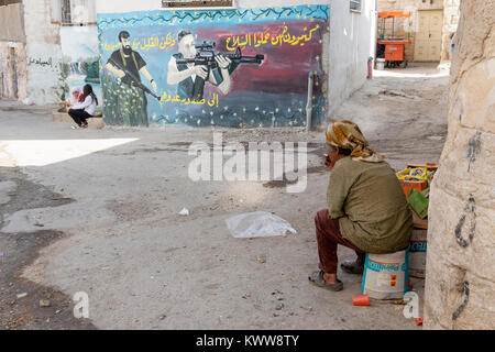 Jénine, Palestine, le 18 novembre 2010 : Une vieille femme palestinienne est à la recherche d'un grand graffiti de martyrs qui se sont battus avec des soldats israéliens à Jénine refuge Banque D'Images