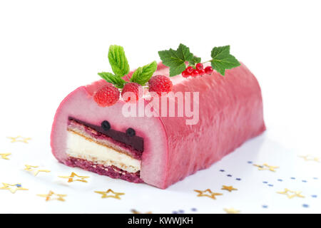 Bûche de mousse au chocolat blanc, farcie de purée de framboise rouleaux éponge, glacé avec de la gelée de framboise, garnie de e, les baies fraîches, groseilles et feuille d'or aussi connu comme Buche de Noel Banque D'Images