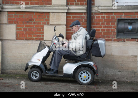 Un homme âgé assis sur un scooter de mobilité à l'extérieur une banque Banque D'Images