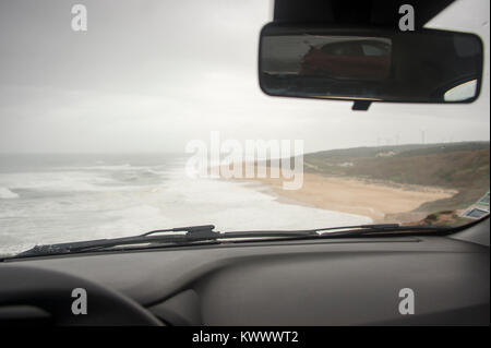 Voir former à l'intérieur d'une voiture en stationnement à la plage un jour pluvieux et venteux en vacances à Praia do Norte Portugal Banque D'Images