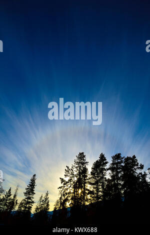 Une verticale de l'image du soleil couchant en faisceaux de lumière briller au-dessus d'une montagne dans le parc national Jasper, Alberta, Canada. Banque D'Images