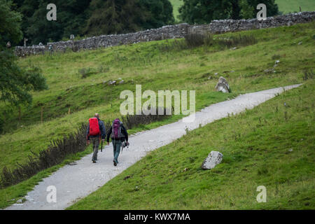 2 mâle randonneurs et promeneurs avec des sacs à dos, marcher ensemble le long sentier national sentier Pennine Way - près de Malham Cove, Yorkshire, Angleterre, Royaume-Uni. Banque D'Images