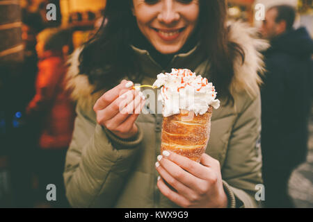 Trdelnik Trdlo ou avec de la crème dans les mains d'une belle fille de l'hiver en République tchèque, Prague au marché de Noël. Banque D'Images