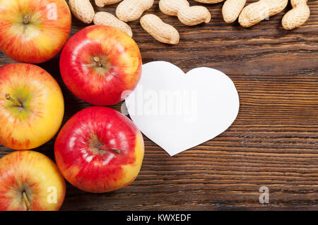 Pommes rouges bien mûrs et d'arachides sur un fond de bois. Vue d'en haut. Concept vegan. Banque D'Images