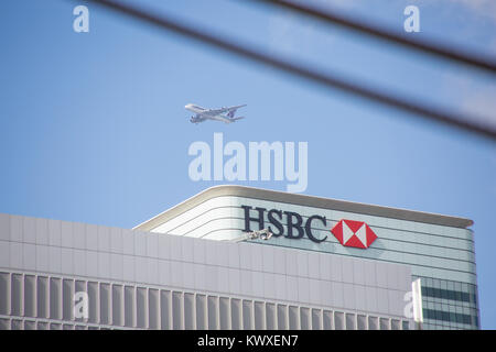 Un avion du passager en vol au dessus du QG de la HSBC à Canary Wharf, Londres Banque D'Images