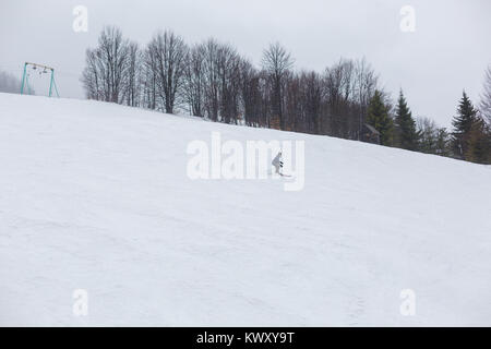 La pente de la montagne est couverte de neige. Le long de celui-ci les arbres pousser. Un skieur est en bas de la pente de ski. Banque D'Images