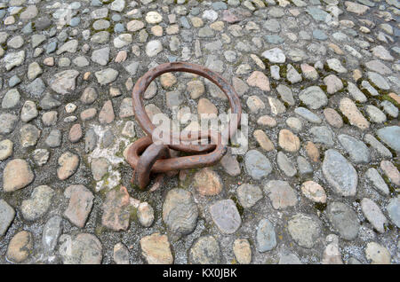 Old rusty anneau d'amarrage à quai dans une rue pavée Banque D'Images