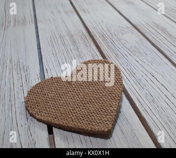 Un gros plan d'un coeur en tissu marron portant sur une table en bois blanc Banque D'Images