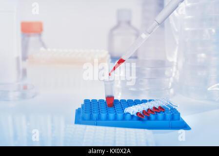 Arrière-plan scientifique en bleu, blanc et rouge. Chargement de l'échantillon liquide avec une pipette automatique, de l'espace pour votre texte. Cette image est tonique. Banque D'Images