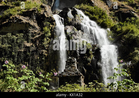 Cascade dans les montagnes au Népal parmi les plantes vertes avec de vieux buddist chorten monument Banque D'Images