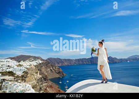 Belle femme en robe blanche avec mariage bouquet sur fond de la mer et l'île de Santorin Banque D'Images