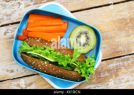 Boîte à lunch saine contenant Brown sandwich au fromage, carottes croquantes et kiwis Banque D'Images