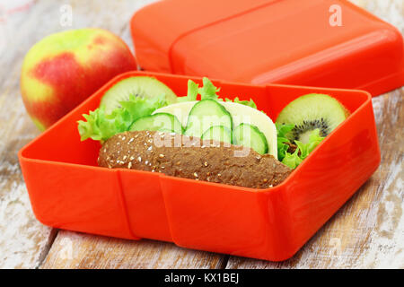 Boîte à lunch saine contenant Brown sandwich au fromage, carottes croquantes et kiwis Banque D'Images