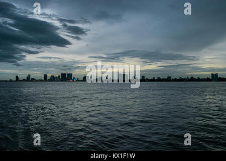 Phnom Penh crépuscule coucher du soleil, vu depuis le Mékong et rivières Tonle Sap, avec sky scrapers émergents. C'est la saison des pluies et des nuages de pluie à l'approche de la ville Banque D'Images