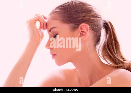 Parution du modèle. Young woman touching forehead, portrait. Banque D'Images