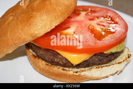 Juteuse Cheeseburger couronné par une tranche de tomate fraîche Banque D'Images