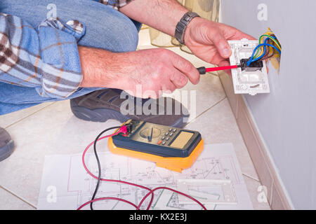 Les mains de l'électricien assemble un bipolaire standard prise murale. Banque D'Images