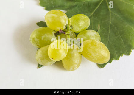 Raisin vert avec des feuilles isolées sur fond blanc. Banque D'Images