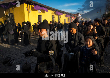 Antigua, Guatemala - Avril 19, 2014 : Gens portant des robes noires dans une rue de la vieille ville d'Antigua au cours d'une procession de la Semaine Sainte à Antigua Banque D'Images