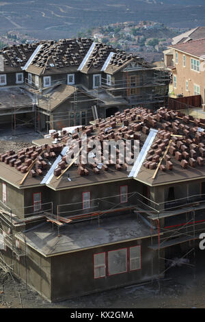 Deux énormes nouvelles maisons en construction dans un quartier Californie développement sur une colline, tuiles empilées sur des toits,échafaudage, prêt pour le stuc. Banque D'Images