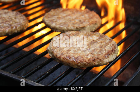 Burgers juteux sizzling plus de flammes chaudes sur le barbecue Banque D'Images