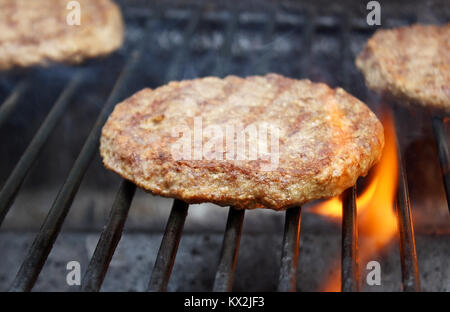 Burgers juteux sizzling plus de flammes chaudes sur le barbecue Banque D'Images