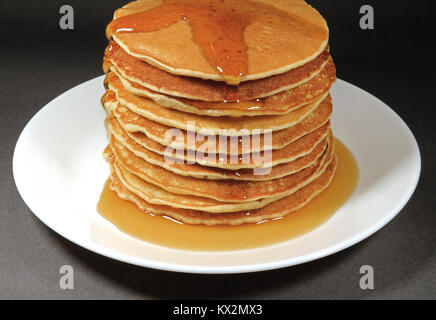 Pile de crêpes maison frais servi avec Sirop d'érable sur plaque blanche, isolé sur fond noir Banque D'Images